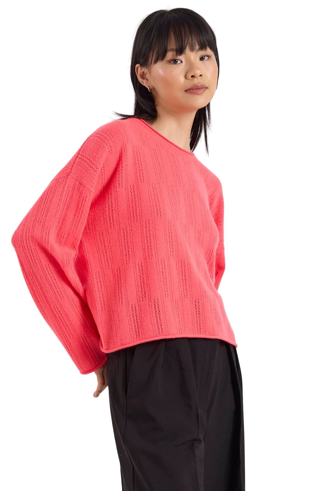 Person wearing a bright pink sweater and black pants on a white background