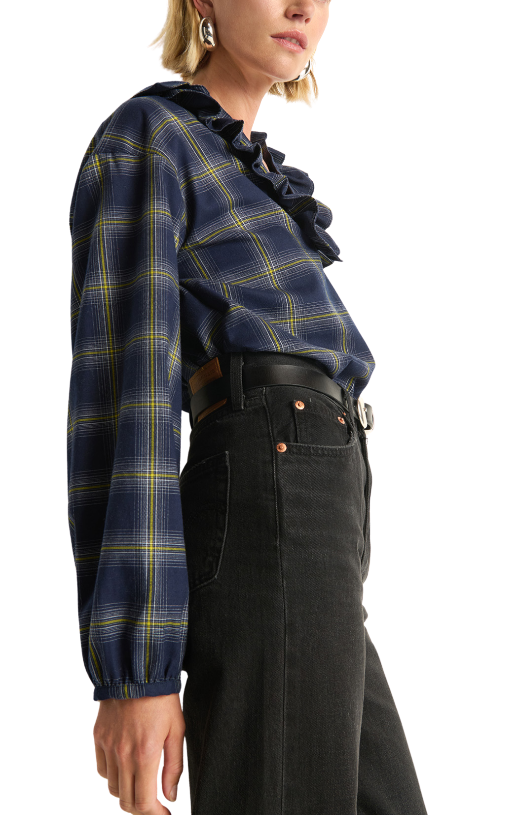 Person wearing a plaid blouse with ruffled details and black pants on a white background