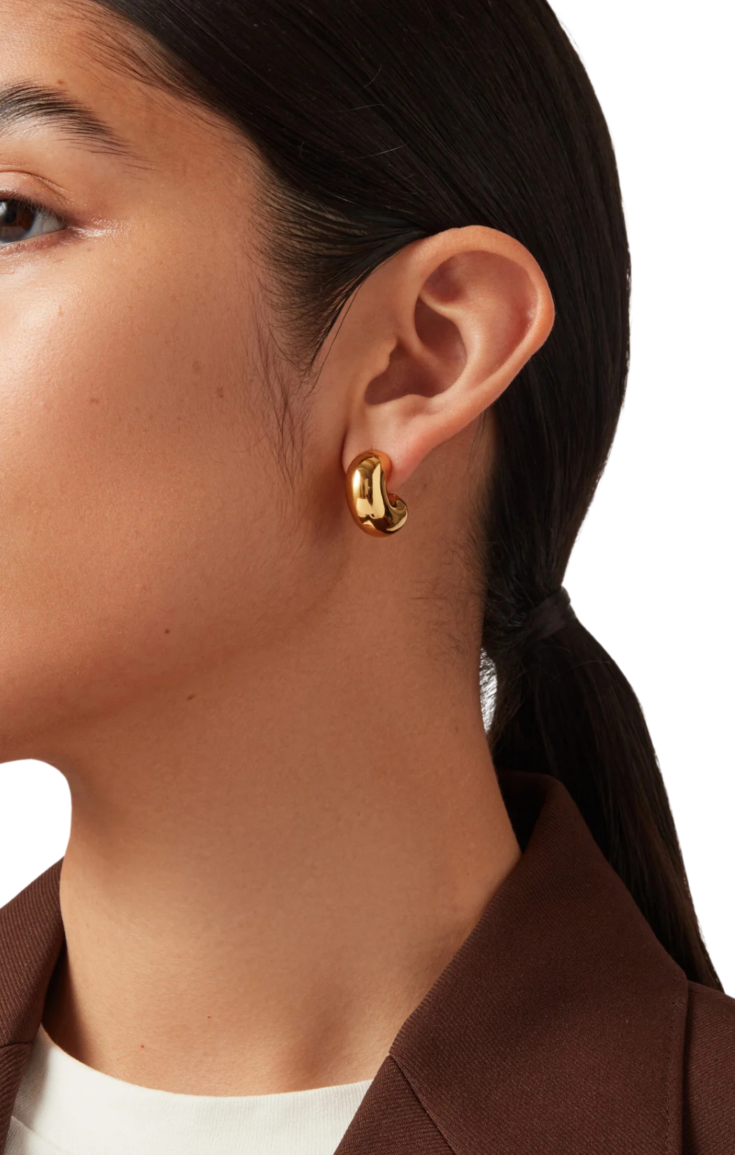 Gold hoop earrings worn by a person with a neutral background