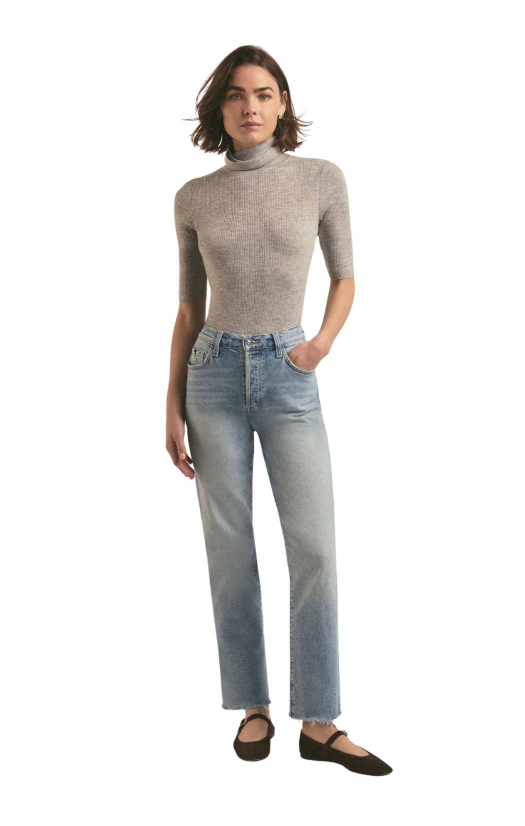 Woman wearing a gray ribbed turtleneck and light blue jeans on a white background