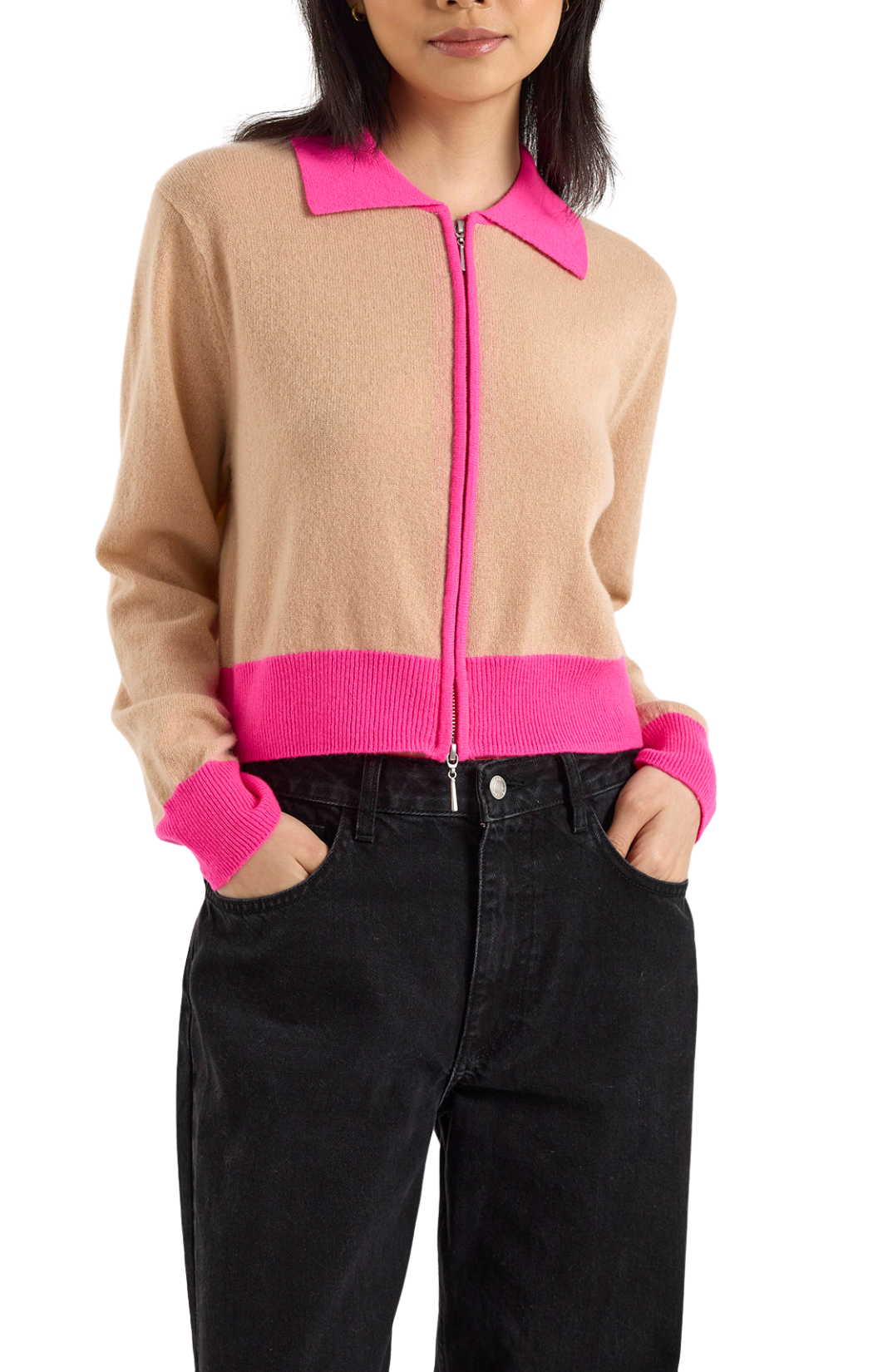 Person wearing a beige and pink zip-up sweater with black pants on a white background
