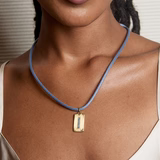 Woman wearing a blue necklace with a gold pendant on a neutral background by Hart 