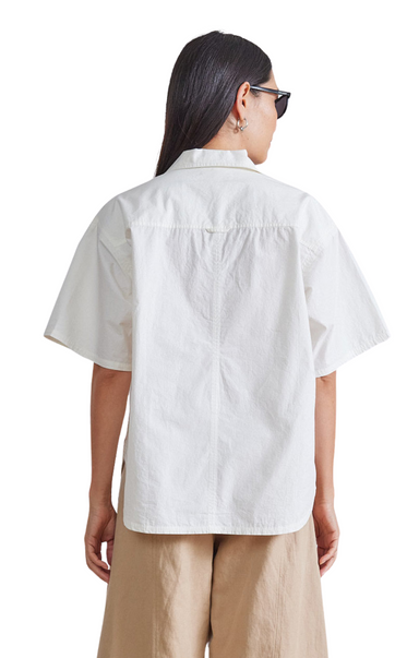 Apiece Apart Easy Pop-Over Henley. White short sleeve. Open neckline, straight silhouette, shirttail hem, side seam slits, short sleeves that can be cuffed
