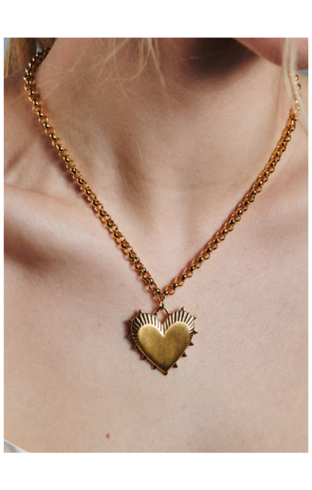 Gold heart-shaped pendant necklace on a person's neck by Hart 