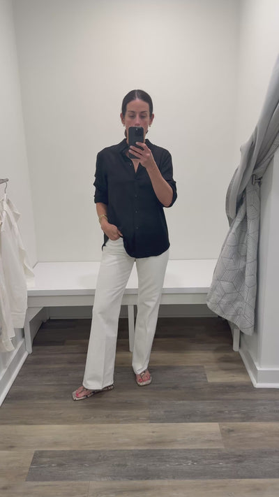 Woman in black linen button  down and white denim. 